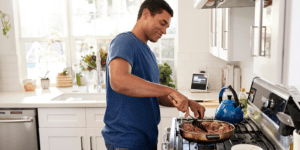 Man cooking a healthy meal at home, symbolizing proactive gut health and naturopathic care for IBS or SIBO in Scottsdale.