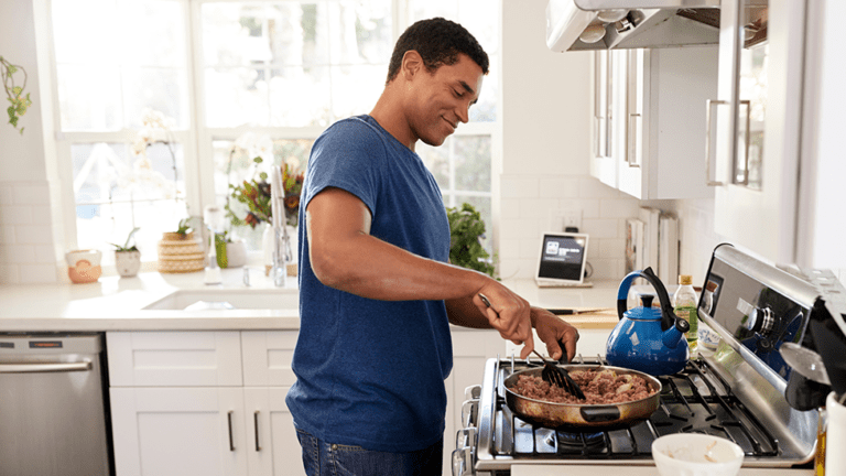 Man cooking a healthy meal at home, symbolizing proactive gut health and naturopathic care for IBS or SIBO in Scottsdale.