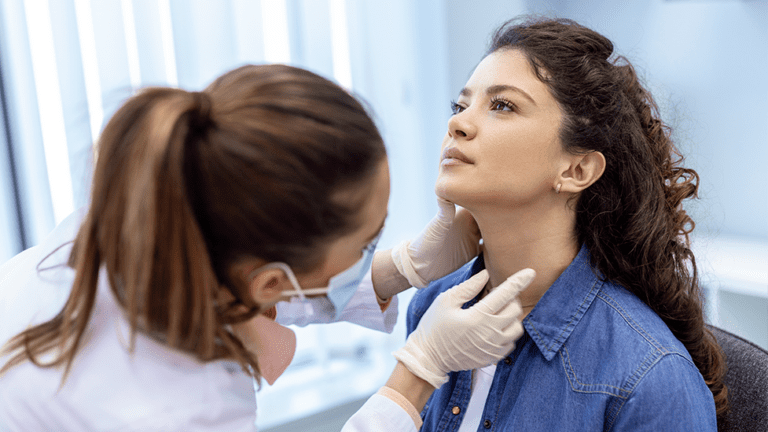 Female healthcare provider examining a young woman's neck and thyroid area during a clinical evaluation for thyroid-related issues.
