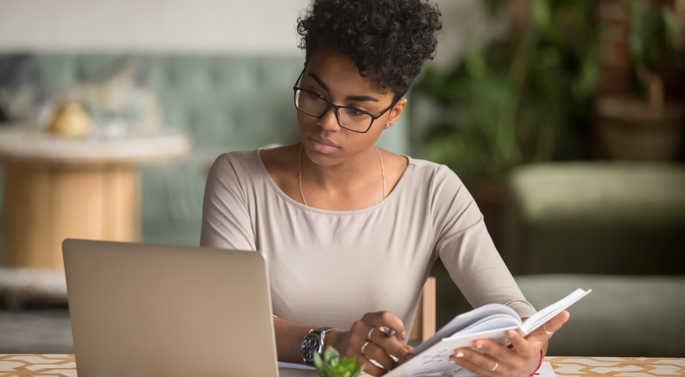 Woman reviewing her blood test results at a laptop while noting questions to bring to her doctor