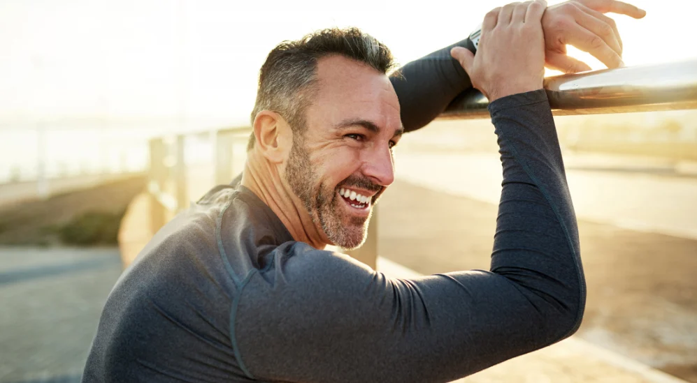 Active middle-aged man stretching outdoors, representing energy and healthy aging